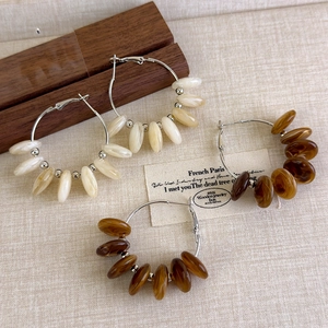 Detailed close-up of French vintage acrylic beaded hoop earrings on a rustic linen surface