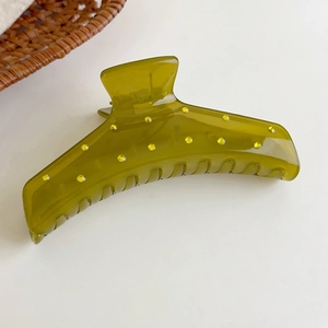 Detalle de una pinza para el cabello verde oliva con efecto gelatina y pequeños brillos
