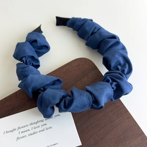 Détail d'un serre-tête en tissu plissé bleu avec texture ondulée et embouts de protection