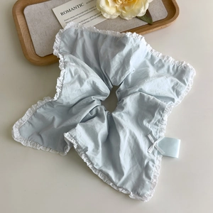Close-up of light blue lace hair scrunchie with white bow and cotton texture details