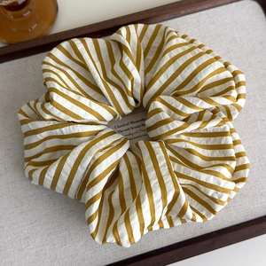 Close-up of a large yellow and white striped fabric scrunchie in a wooden tray