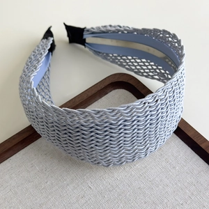 Detail of light blue woven bohemian headband with intricate cross-knit texture