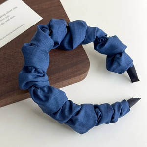 Vue détaillée de la texture en denim bleu plissé sur un serre-tête rembourré et ondulé