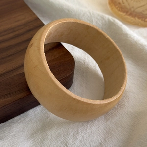 Macro shot of minimalist natural light wood wide bangle with smooth grain and thick texture