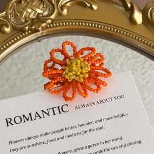 Macro shot of orange beaded flower shoe charm on a romantic vintage display card