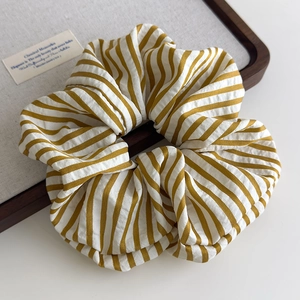 Macro detail of high-quality yellow and white striped fabric scrunchie with soft texture