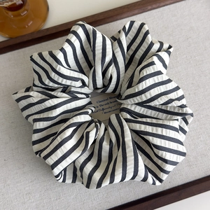 Detailed view of striped black and white cotton scrunchie on a warm lifestyle background