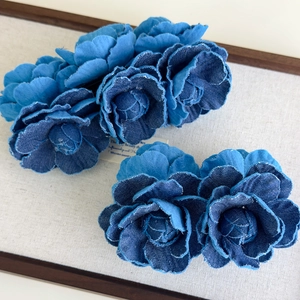 Detail of handmade denim camellia hair clip showing layered blue fabric and frayed edges