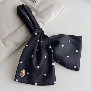 Close-up of black satin polka dot bow tie with zipper adjustment and gold metal accent