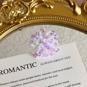 Detail of handcrafted purple crystal bead flower charm for shoes on artistic card