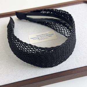 Close-up of black bohemian woven hollow headband with detailed texture on linen tray