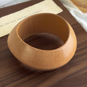 Macro shot of thick wood bangle featuring natural grain on retro lace background