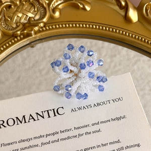 Detailed view of handmade blue crystal and white seed bead flower charms for DIY shoes