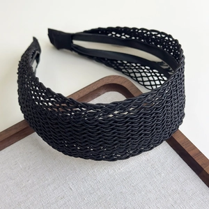 Close-up of black braided mesh headband showing delicate hollowed-out texture on linen fabric