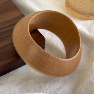 Macro view of geometric wooden wide bangle featuring natural wood grain and angled facets