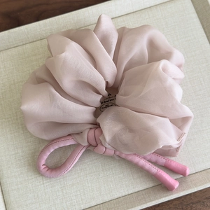 Close-up of pink oversized chiffon scrunchie with woven knot detail in a gift display box