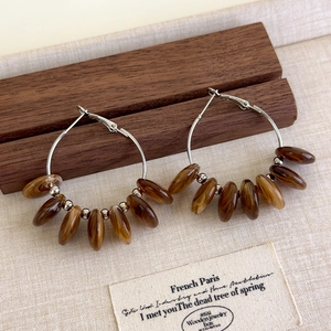 Detailed close-up of French vintage amber resin beaded hoop earrings on a wooden stand