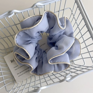 Detail of light purple chiffon scrunchie with cream trim in a white wire basket
