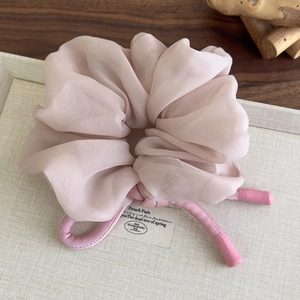 Detailed close-up of pink organza scrunchie with long ribbons on a textured surface