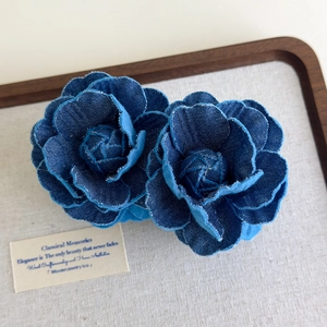 Detailed macro shot of handmade blue denim camellia hair clips on a vintage linen tray