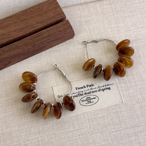 Detail of amber acrylic beads and silver hoop earrings on vintage fabric background