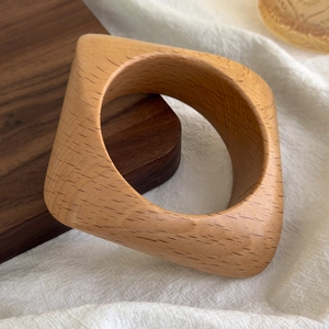 Detail of natural beech wood geometric bangle showing irregular wood grain and smooth finish