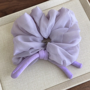 Detail view of a lavender chiffon scrunchie with long ribbon tails on a display tray