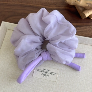 Detail of purple chiffon scrunchie with rabbit ear bow on a natural wooden display