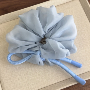 Detail of light blue chiffon scrunchie with long ribbon on a textured tray