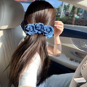 Three deep blue denim camellia flowers hair clip worn on a high ponytail for women