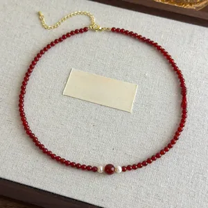 Detail of red agate beads and pearls on a vintage necklace with golden extension chain