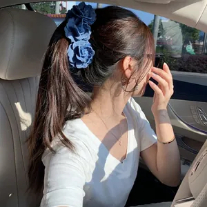 Handmade denim camellia hair clip showing vertical flower arrangement on a ponytail