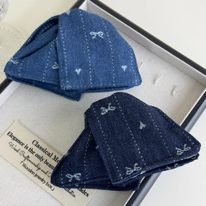 Détail de la texture du tissu denim avec motifs de cœurs et nœuds sur les pinces à cheveux