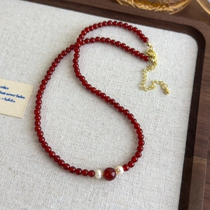 Detail of red agate bead necklace with white freshwater pearls on a wooden tray
