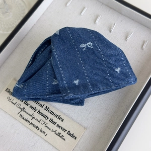 Gros plan sur une pince à cheveux en denim avec broderies de cœurs et papillons argentés