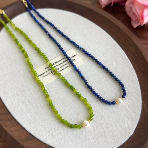 Detail of freshwater pearl necklace with lapis lazuli and gold beads on wooden tray