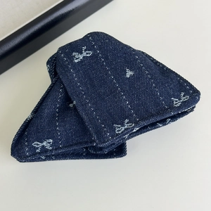 Détail d'une pince à cheveux en denim bleu foncé avec motifs nœuds blancs et texture