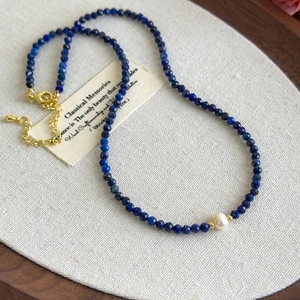 Detail of blue lapis lazuli beaded necklace with white pearl and gold hardware