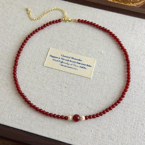 Macro shot of vintage red beads and pearl necklace with golden clasp on linen