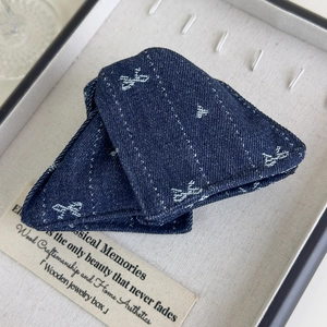 Détail de la pince à cheveux en denim bleu foncé avec nœuds brodés et texture fine