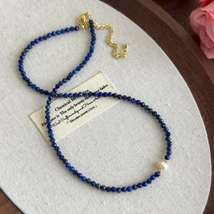 Detailed macro view of lapis lazuli beads with a white pearl and gold adjustable chain clasp