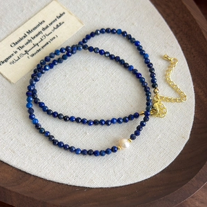 Detailed view of blue lapis lazuli beaded necklace with single freshwater pearl and gold clasp