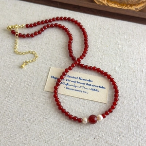 Vintage red agate beaded necklace with pearls and gold accents on a beige background