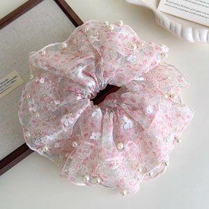 Detail van roze bloemen kant scrunchie met witte parels op een esthetisch dienblad