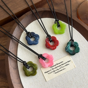 Colliers pendentifs fleurs en acrylique coloré avec texture marbre sur plateau bois