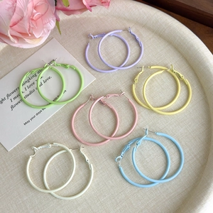 Set of six pairs of large macaron-colored matte hoop earrings on a decorative tray