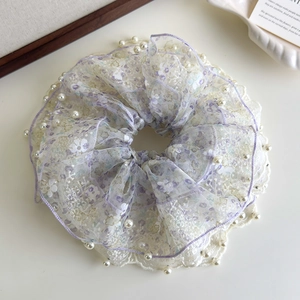 Macro-opname van lichtpaarse bloemen kant scrunchie met parels en organza stof