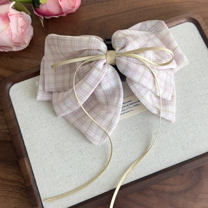 Close-up of pink checkered bow hair claw clip with delicate gold ribbon details
