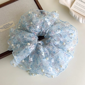 Detailopname van lichtblauwe kanten scrunchie met bloemenprint en witte parelaccenten