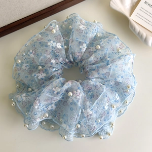 Macro-opname van blauwe bloemen kant scrunchie met witte parels en organza textuur